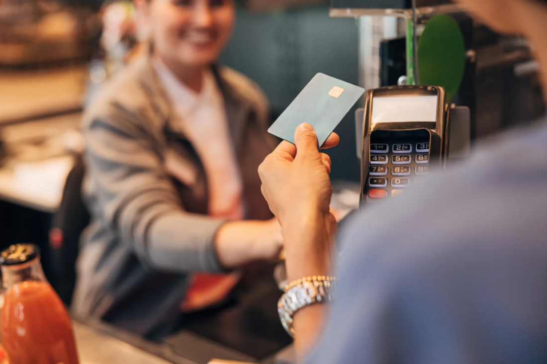 A customer tapping a card at a point-of-sale payment terminal in a shop